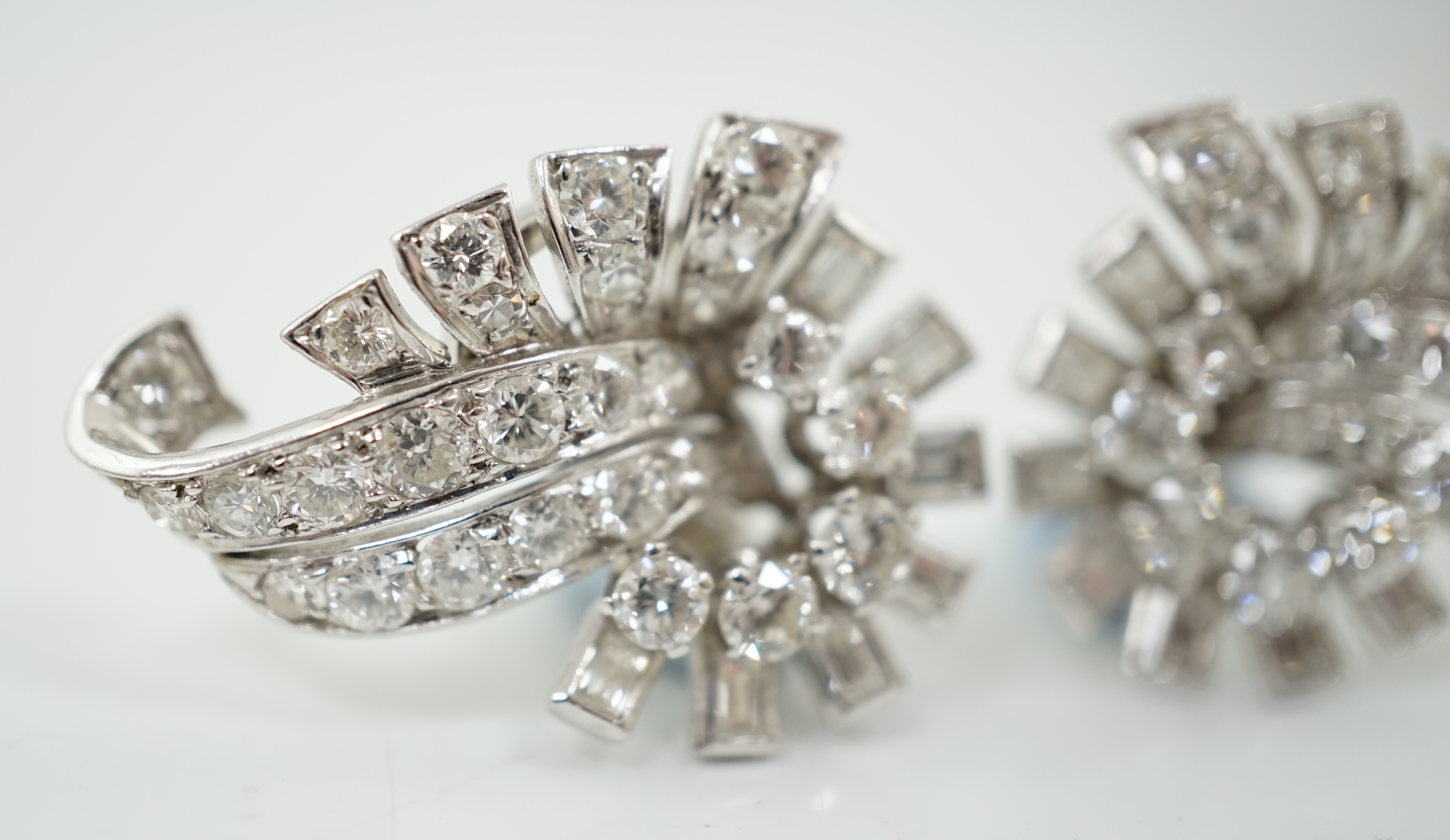 A pair of platinum and diamond cluster scroll ear clips